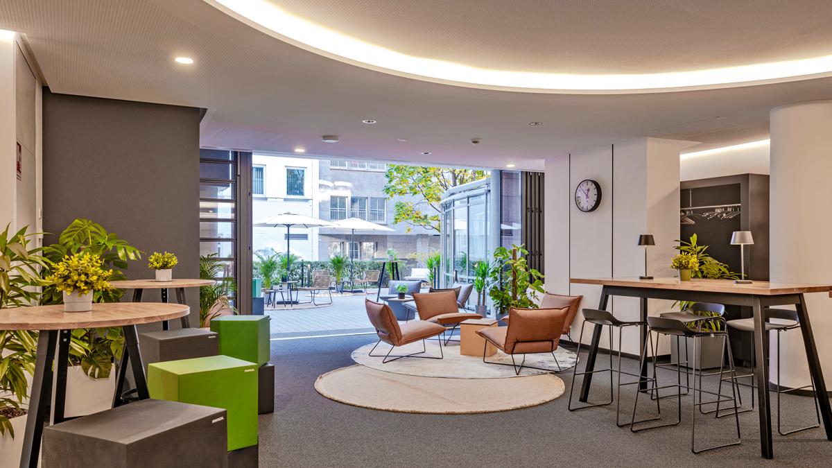 memox Lobby mit braunen Ledersesseln, rundem Teppich und Blick zur Terrasse